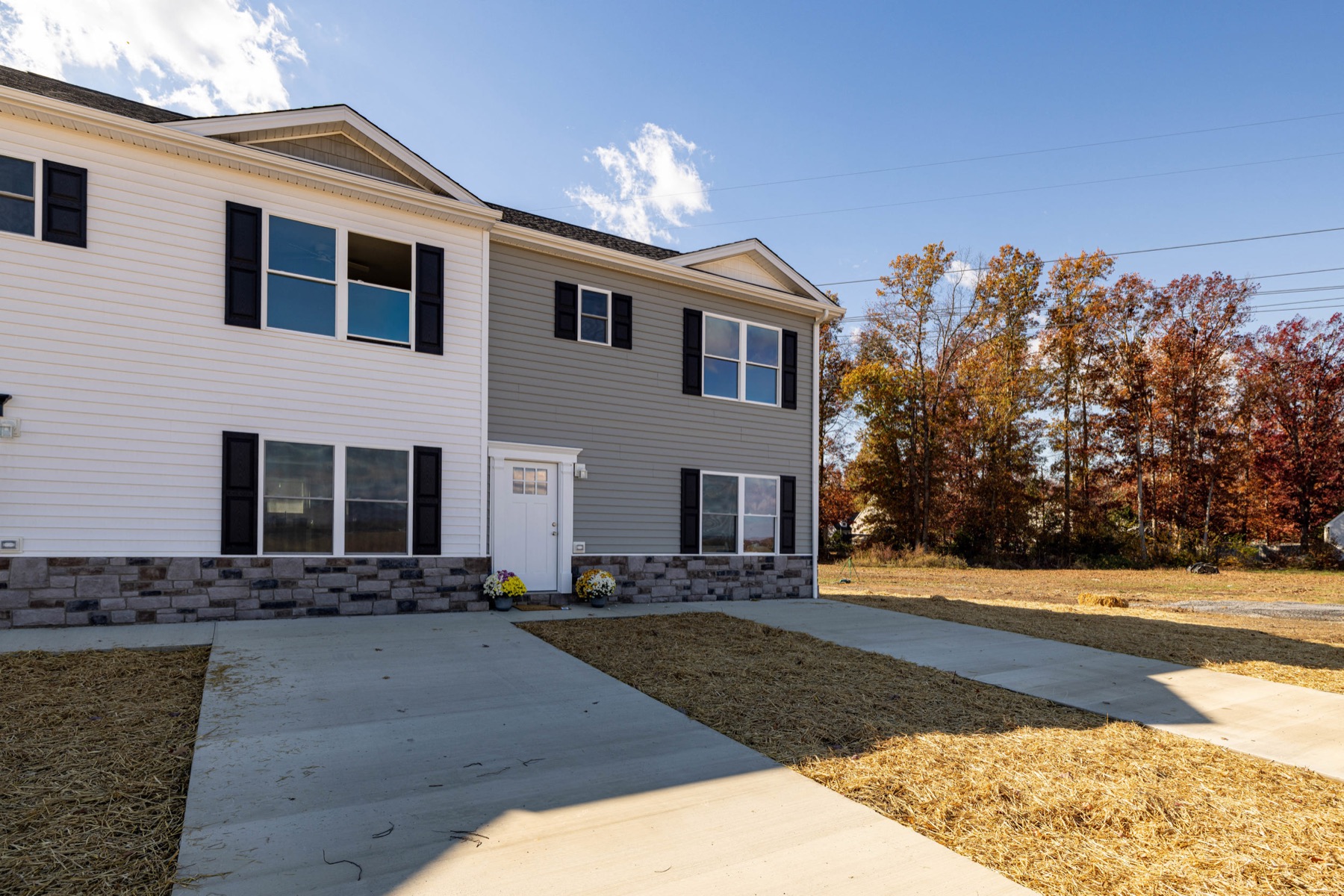 Front of completed Forest Station townhomes with two-tone siding, black shutters, stone-veneer base and driveway parking