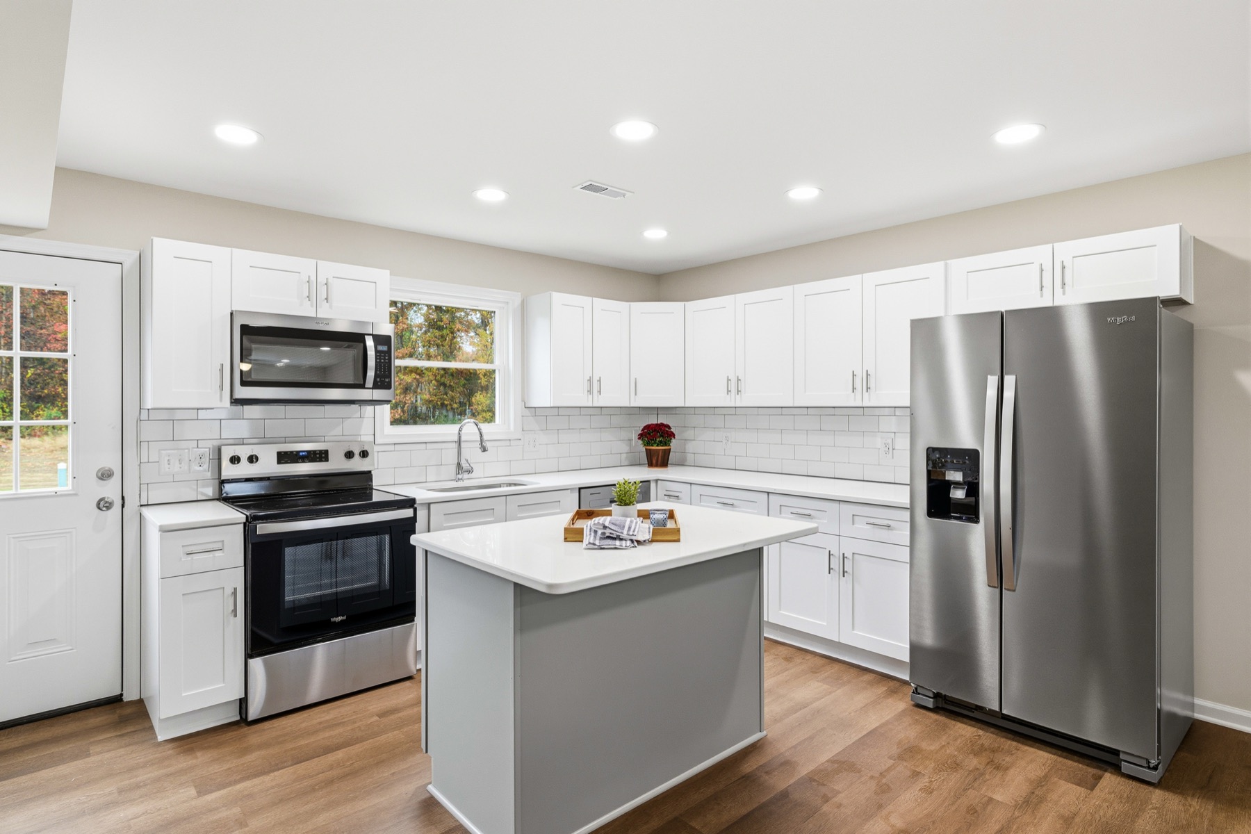 Kitchen with white shaker cabinets, a center island, quartz counters and stainless appliances