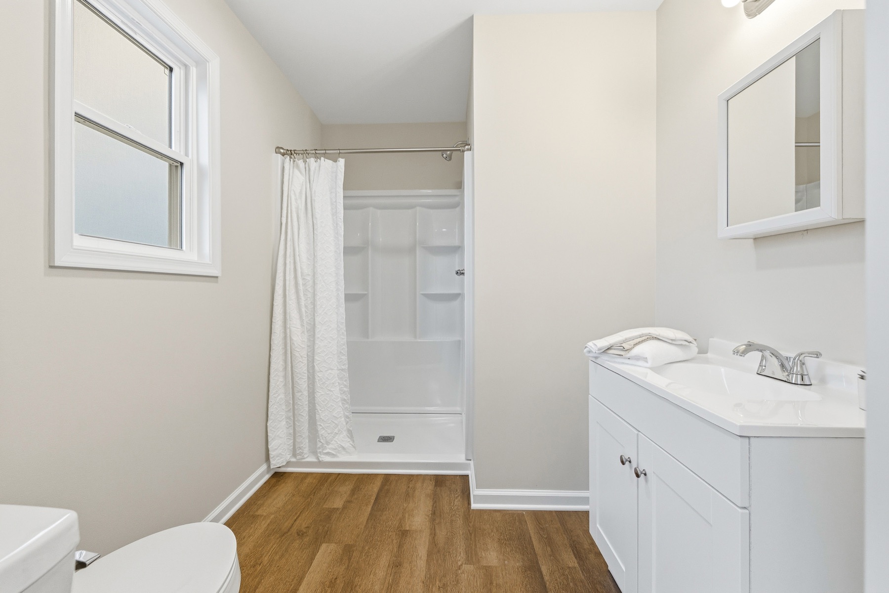 Primary ensuite bath with walk-in shower and white vanity
