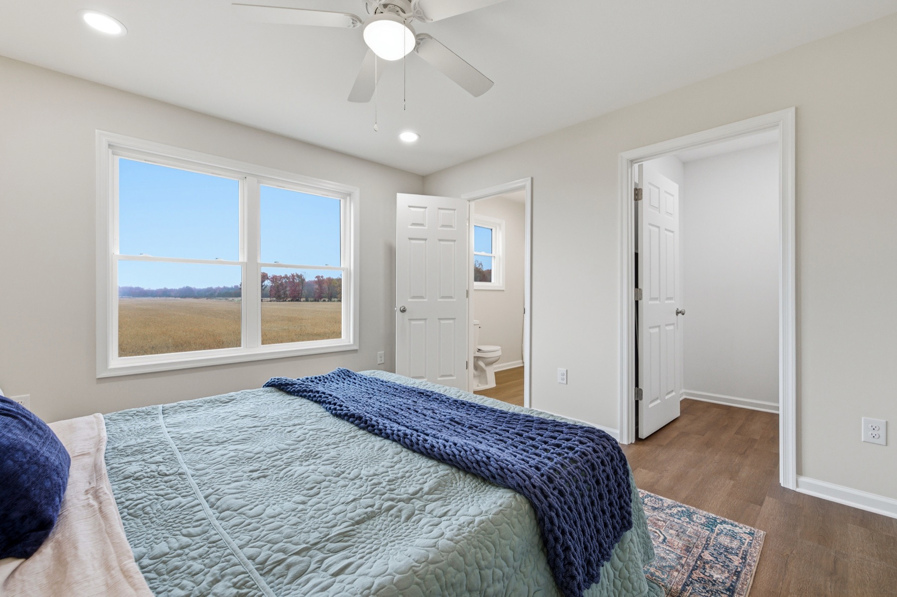 Primary bedroom with a window looking out over open farmland